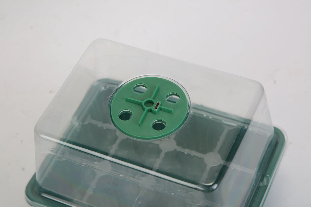 Clear humidity dome fitted over a green seed starter tray.