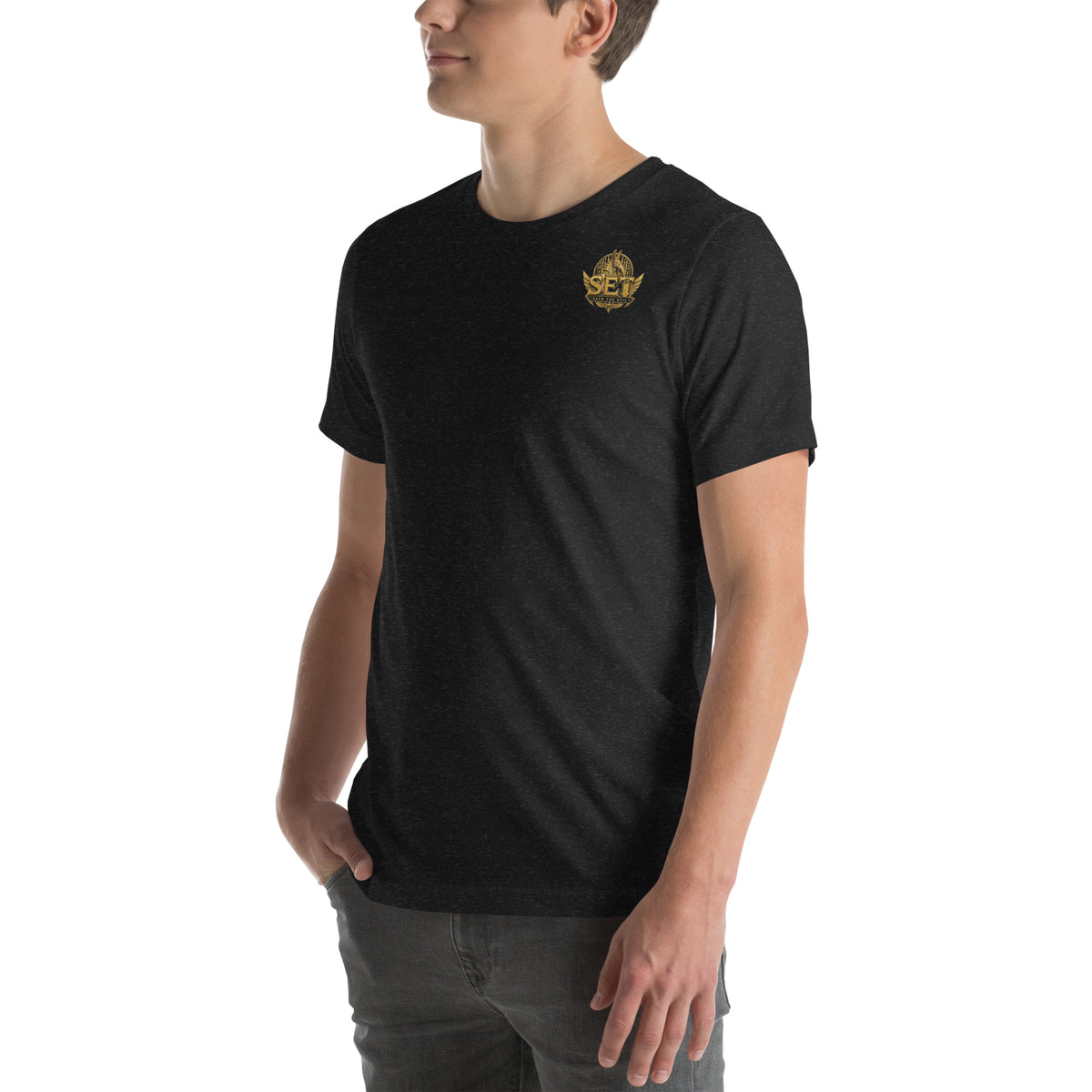 Black heather unisex staple T-shirt with the gold-tone SET Anubis crest on the wearer’s left chest — front-left view.